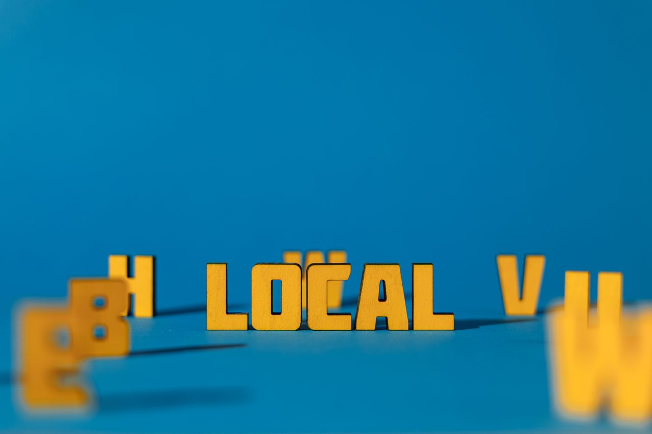 Abstract image featuring yellow wooden letters spelling 'LOCAL' on a blue background, offering ample copy space.